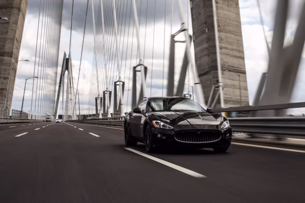 black-sedan-car-driving-bridge-road_114579-4023