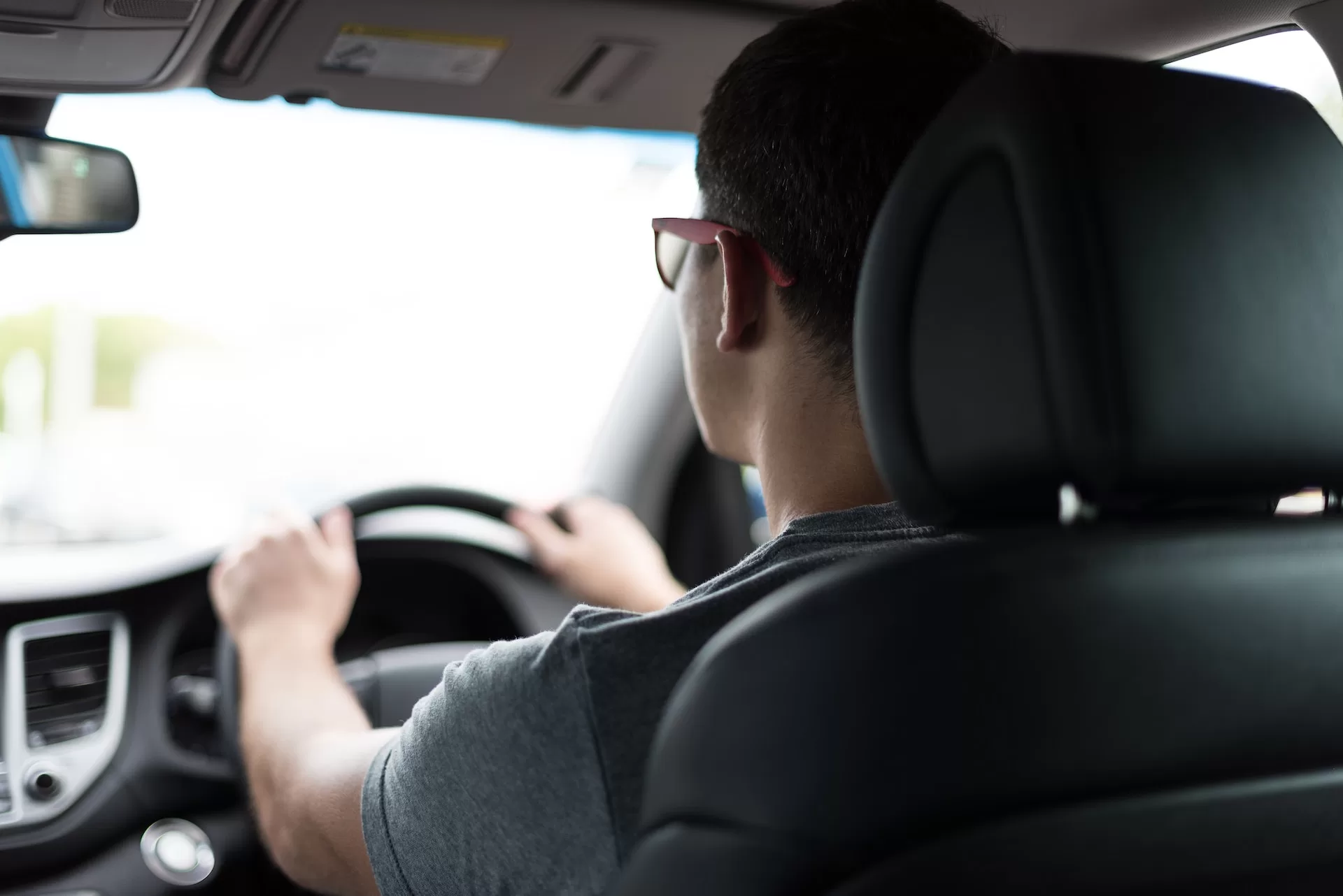 Sopir profesional sedang mengemudikan mobil rental dengan aman sambil membawa penumpang dalam perjalanan.